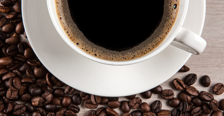 white cup of coffee against a background of fried coffee beans