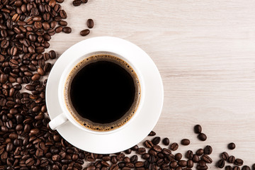 white cup of coffee with coffee beans on a wooden  background