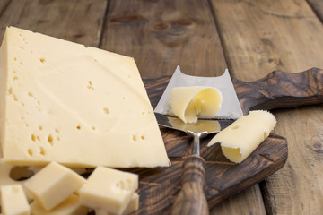 Cheese with holes large and small. Wooden board and knife. Traditional Dutch cheese. Copy space
