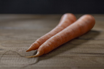 two raw young carrots on a dark background