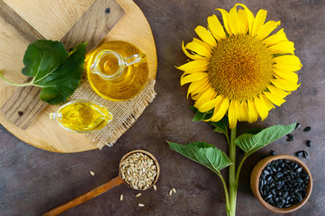 A large sunflower, a bottle of oil, seeds on the table. Top view. Manufacture of sunflower oil.