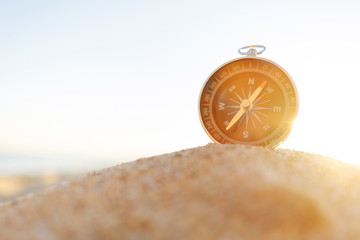 Compass on sand on sunny day.