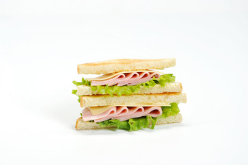 A triangular shape sandwich on a white background. The filling of the sandwich consists of lettuce, ham, cheese and fresh vegetables. Close-up.