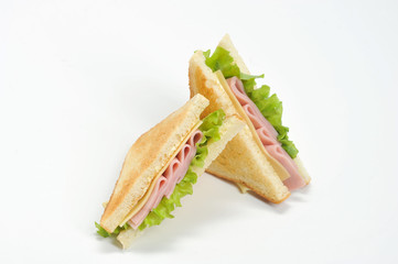 Two triangular sandwiches with cheese and ham. The sandwich is made from slices of fried white bread. Close-up. White background.