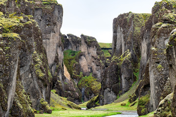 Landscape closeup of canyon in Fjadrargljufur, Iceland with large cliffs, river, green moss grass
