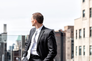 Young businessman standing in business suit looking over shoulder at New York City cityscape...