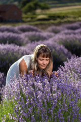 Young woman in a white dress smelling lavender blossoms