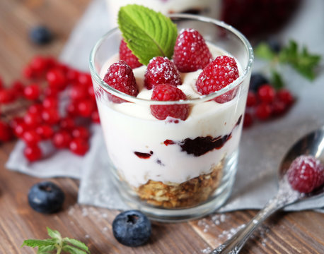 healthy eating and diet concept: Happy breakfast - yogurt with muesli and berries on a wooden table