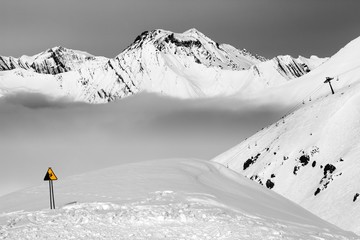 Warning sing on snowy ski slope and mountains in haze