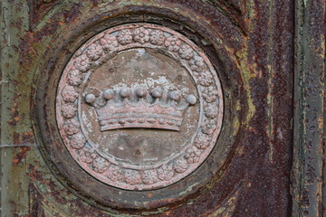Part view of an old, rusty door of a crypt in Berlin-Germany. A weathered crown