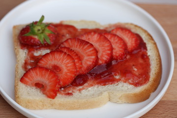 Bread slice with jam and strawberries.