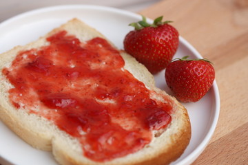 Bread slice with jam and strawberries.