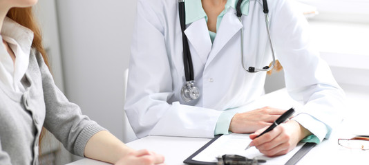 Doctor and  patient  sitting at the desk near the window in hospital