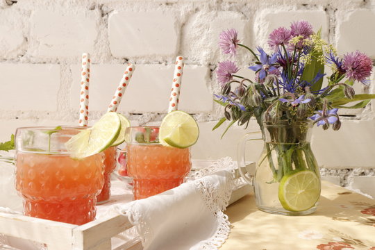 Pink grapefruit juice in glasses with straws.