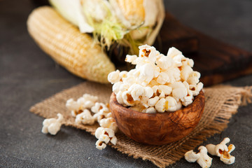 Popcorn in a olive wooden bowl on a dark background