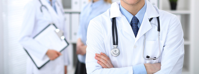 Doctor man standing straight in hospital office. Closeup of stethoscope at practitioner breast. Medicine and health care concept