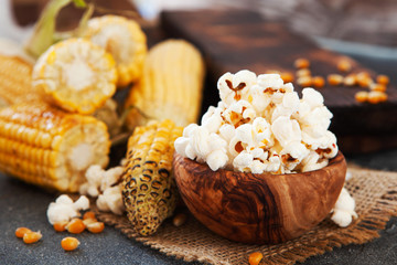 Popcorn in a olive wooden bowl on a dark background