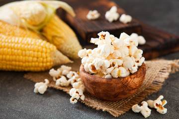 Popcorn in a olive wooden bowl on a dark background