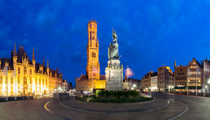 Naklejka premium Wieża Belfort i posąg Jana Breydela i Pietera de Conincka na Grote Markt lub Rynku podczas niebieskiej godziny wieczornej, Brugia, Belgia
