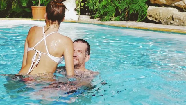 Happy couple in love having fun in pool playing slow motion closeup