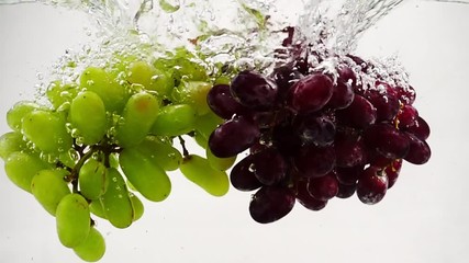 Red and green grapes falling into water with bubbles in slow motion. Fruit on white background. - Powered by Adobe