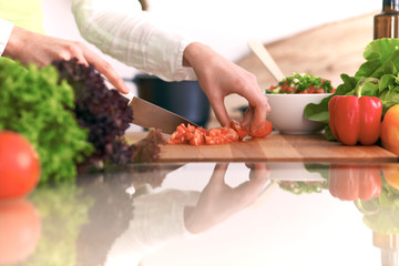 Close Up of human hands cooking vegetable salad in kitchen on the glass table with reflection. Healthy meal, and vegetarian food concept