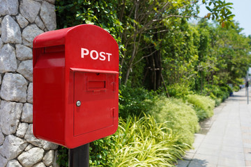 Red mail box trees and grass on a street stone wall