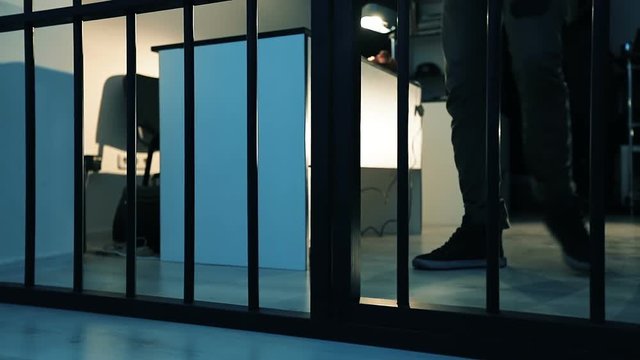 A policeman leads a criminal into the prison cell.