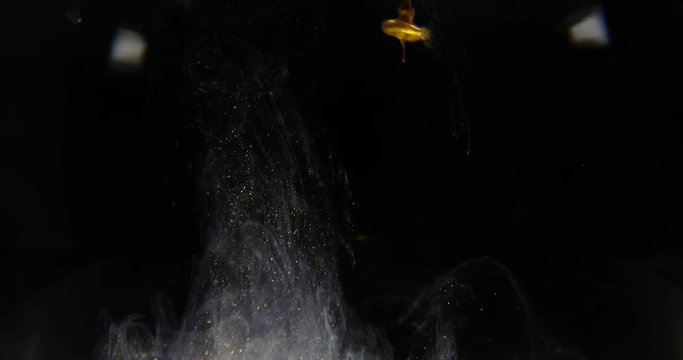 Golden paint cloud with glitter in water isolated on black background