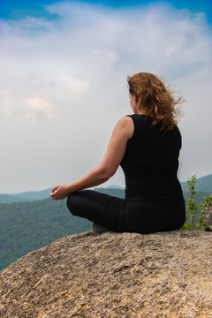 On a mountaintop/ Young female rock climber meditating on top of a mountain