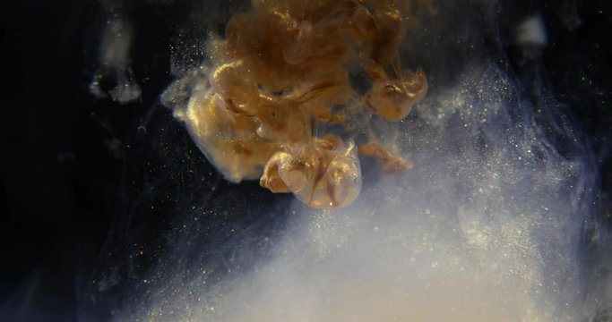 Golden paint cloud with glitter in water isolated on black background