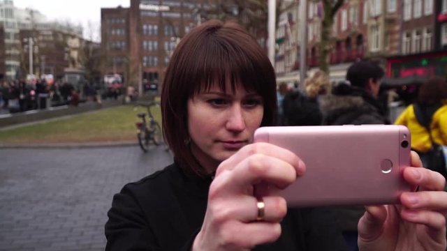 Woman tourist takes pictureson on smartphone the city. Amsterdam Rembrandtplein . slow motion