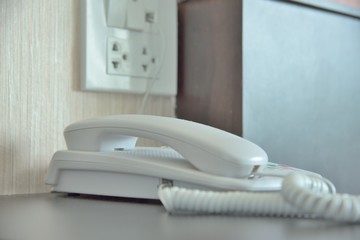 Phone on a table near a plug. 