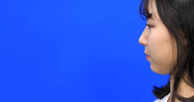 Asian beautiful girl pulling something invisible toward her on blue screen