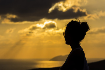 Woman silhouette over an horizon dominated by the sunset over the Greek Islands at Crete