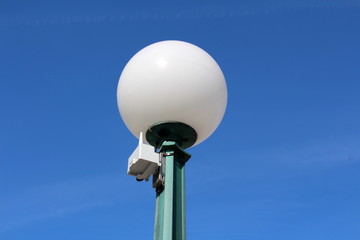 Street lamp post with small wireless antenna on clear blue sky background