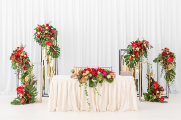Fototapeta premium Beautiful banquet hall under a tent for a wedding reception. Interior of a wedding tent decoration ready for guests. Decor flowers. Red theme