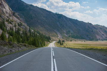 Fototapeta premium Landscape with empty road and mountains. A road winds through a mountain pass in horizontal perspective