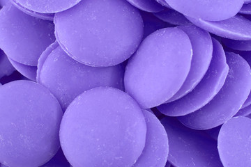 Violet candy chocolate background, copy space. Closeup of pile chocolate button candies. Candy texture. Candy pattern. Sweets background. Top view, flat lay