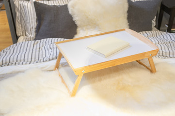 Obraz na płótnie Canvas Tray table with book on a bed closeup