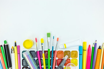 paints, pencil, brushes, markers on white desk background with copy space, flat view