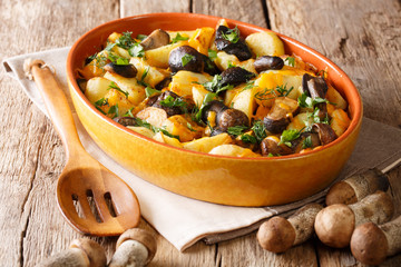Fried wild mushrooms with potato slices, dill, parsley and cheddar cheese close-up on a table. horizontal