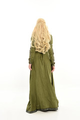 full length portrait of blonde girl wearing green medieval gown, standing pose facing away from camera. isolated on white studio background.