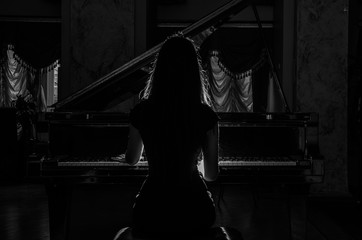 Young charming brunette girl playing the piano