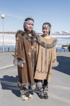 Two chukchi girls in folk dress against the Arctic landscape