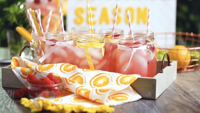 Raspberry lemonade garnished with fresh lemon and raspberries in drinking mason jars