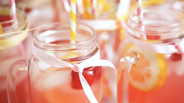Raspberry lemonade garnished with fresh lemon and raspberries in drinking mason jars