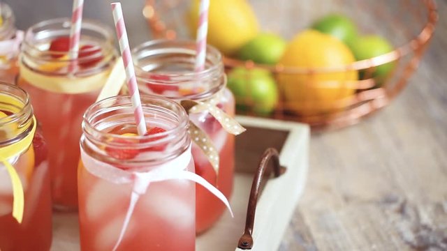 Raspberry lemonade garnished with fresh lemon and raspberries in drinking mason jars