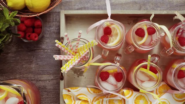 Raspberry lemonade garnished with fresh lemon and raspberries in drinking mason jars