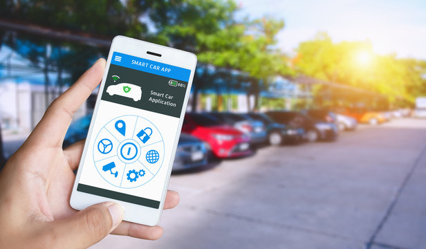 Hand Holding Smart Phone And Application Dashboard With Blur Car Parking Background.